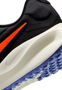 Zapatilla deportiva negra con superior de tela texturizada, un logo naranja y una entresuela blanca. La suela exterior tiene un patrón de goma azul para mayor agarre.