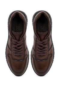 Bruine lederen sneakers met een gladde textuur, voorzien van donkere veters, perforaties op de neus en een stevige zwarte rubberen zool.