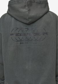 Felpa blu scuro con un tessuto strutturato. Presenta un grande logo in rilievo sul retro e un testo stampato sottile in nero. La felpa ha un cappuccio profondo.