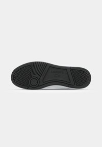 Talpa de pantof din cauciuc negru, cu un model striat, având logo-ul embosat "LACOSTE" și toc rotunjit. Texturată pentru aderență și stabilitate.