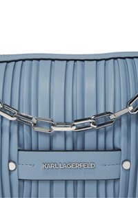 Vaaleansininen laskostettu nahkalaukku, jossa on hopeinen ketjuhihna ja etupaneelissa teksti "KARL LAGERFELD".