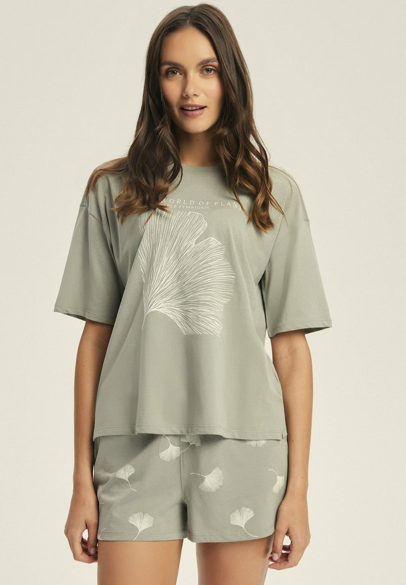 Jasnozielona bawełniana koszulka z krótkim rękawem i dużym białym wzorem liścia. W komplecie z dopasowanymi szortami z podobnym wzorem liścia.