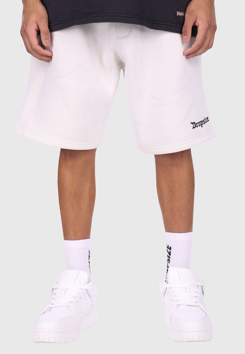 Hvide bomulds shorts med sidesøm, med "Dropside" trykt i sort. Båret med hvide sneakers og hvide ribbede sokker.