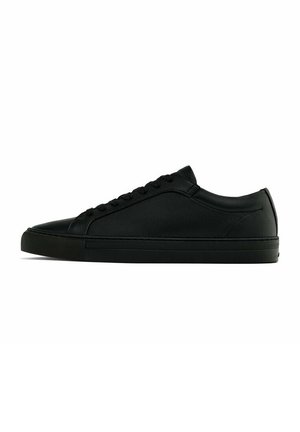 Low-top sort læder sneakers med sorte snørebånd og en flad gummisål vist i sideprofil på en hvid baggrund.