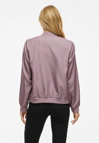 Giacca bomber in raso di un leggero colore viola, con colletto e polsini a costine, caratterizzata da un orlo arricciato e una texture morbida.