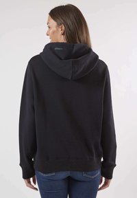 Sweatshirt à capuche noir avec une coupe décontractée et un ourlet texturé. Le tissu semble doux, avec une subtile accent pailleté sur les poignets.