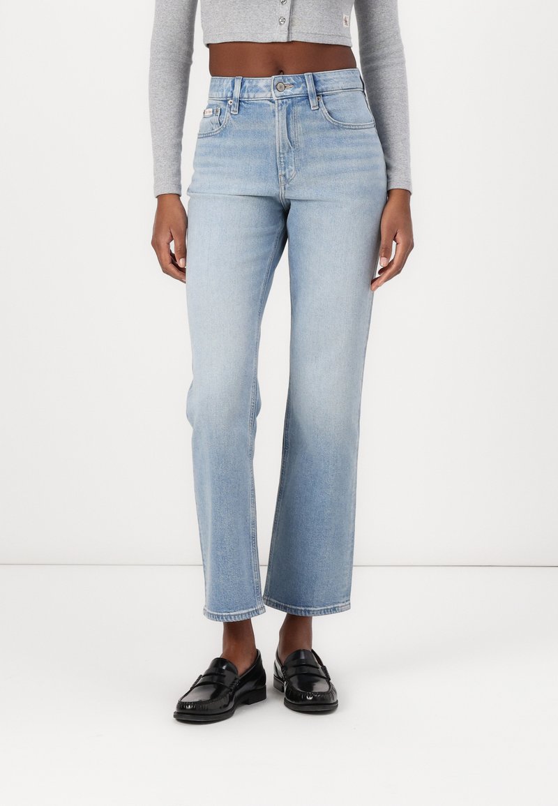 Jeans azzurri chiari a vita alta con taglio dritto, dotati di chiusura a bottone, cinque tasche e dettagli di scoloritura minimi.