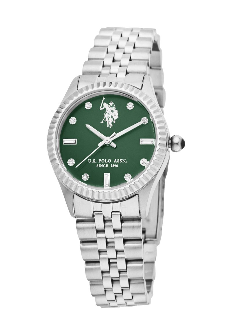 Montre en acier inoxydable argenté avec un cadran vert, rehaussée de marqueurs en cristal et d'un logo argenté. Caractérisée par une lunette texturée et un bracelet à maillons.