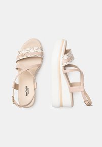 Sandali con plateau in pelle beige crema, caratterizzati da morbidi incroci sulla parte superiore e una fascia in tessuto con motivo. Suola spessa bianca con dettagli laterali.