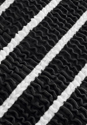 Mustvalge kude, millel on vahelduvad ripsmetega triibud. Tekstuur on kokku kogutud ja paks, suurendades värvide vahelisi visuaalseid kontraste.