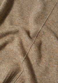 Tissu en laine marron doux avec couture visible et texture subtile, légèrement froissé et plié.