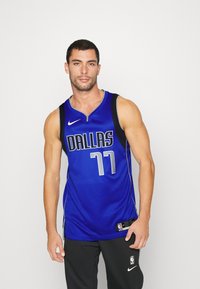 Maillot de basket-ball bleu arborant le mot "DALLAS" et le numéro "77" en argent. Fabriqué en tissu respirant avec un design en col en V.