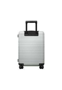 Silver suitcase with horizontal grooves, a telescoping handle, and four black rolling wheels. Smooth texture and minimalist design.