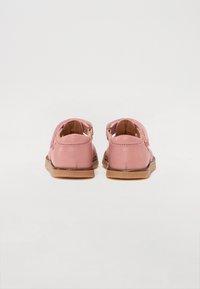 Rosa skor med mjuk textur, låg profil och sula av naturligt gummi. Har en slip-on design och dubbla remmar för säker passform.