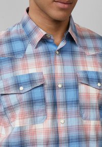 Karobluse mit kurzen Ärmeln in Blau, Rot und Weiß, die einen Button-Down-Kragen, zwei Brusttaschen und ein farbenfrohes Karomuster aufweist.