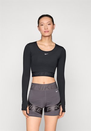 Crop top noir à manches longues avec logo et short taille haute gris avec des accents de logo foncé. Tissu lisse avec un design ajusté.