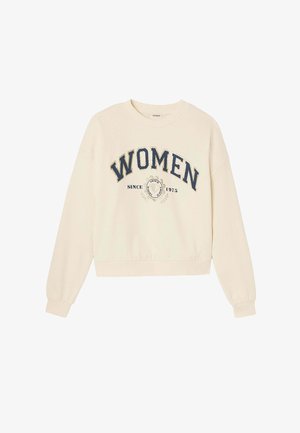 Sweatshirt couleur crème avec un col rond, des manches longues et une coupe courte. Présente le texte "FEMMES" et un graphique "DEPUIS 1975" en marine. Texture douce.