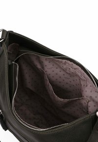 Zelená kožená kabelka se stříbrným zipem. Interiér má fialovou podšívku s puntíkovaným vzorem a vícero kapsami.