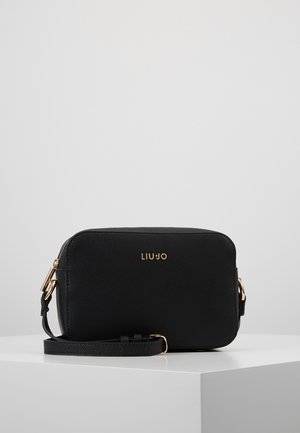 Schwarze rechteckige Umhängetasche mit goldfarbenen Beschlägen, strukturierter Oberfläche und "LIU JO"-Logo auf der Vorderseite, präsentiert auf einem weißen Podest.