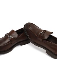 Brown leather loafers with a rounded toe, featuring a decorative metal buckle accent. Smooth texture and low block heel design.