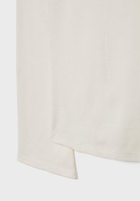 Cream-colored ribbed cotton t-shirt featuring short sleeves, a straight hem with split sides, and a soft, textured surface.