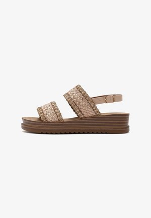 Woven fabric sandals with two wide straps, beige color with green accents, and a brown layered sole featuring a zigzag pattern.
