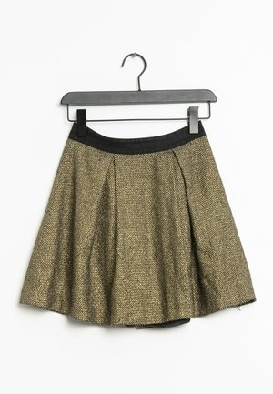 Une jupe plissée en tissu texturé doré et noir, avec une ceinture noire, accrochée à un cintre en plastique noir.