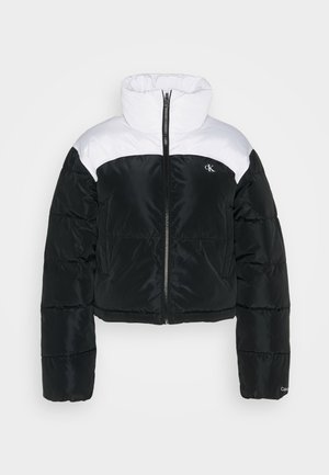 Zwart-witte pufferjack met een hoge kraag, cropped ontwerp en ritssluiting aan de voorkant. Beschikt over een logo op de linkerborst en geribbelde manchetten.