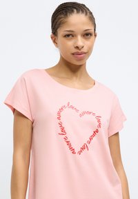 Ροζ βαμβακερό T-shirt με στρογγυλή λαιμόκοψη και κοντά μανίκια, με κόκκινο κεντημένο κείμενο σε σχήμα καρδιάς που επαναλαμβάνει τη φράση "amore love".