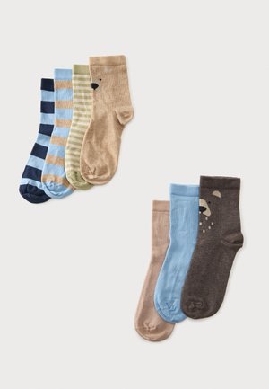 Dos juegos de calcetines infantiles, uno de tres y otro de cuatro pares, en varios colores y patrones, incluyendo rayas y caras de osos, sobre un fondo claro.