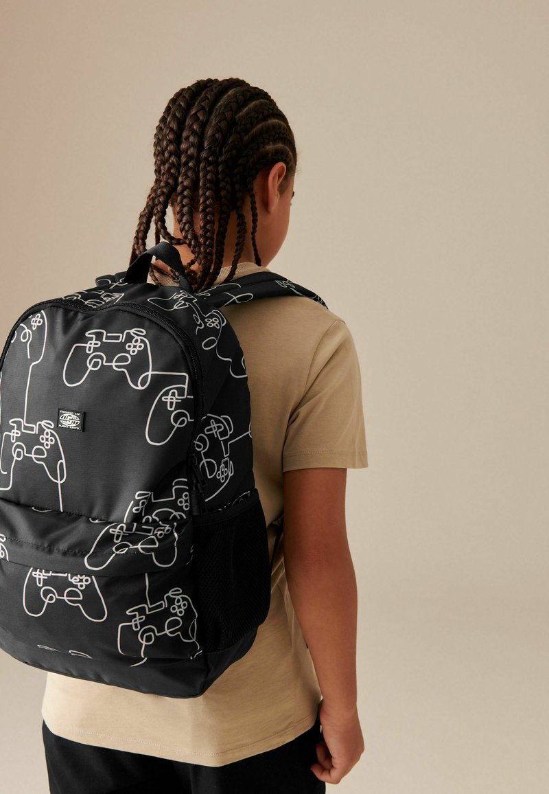 Schwarzer Rucksack mit weißen Mustern von Gaming-Controllern, Reißverschluss, doppelten gepolsterten Riemen und einer seitlichen Netztasche. Auf einem neutralen Hintergrund.