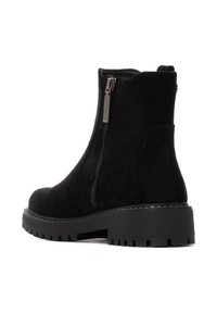 Botines de ante negro con cremallera lateral, un acabado texturizado y una suela de goma negra gruesa con patrones de tracción pronunciados.