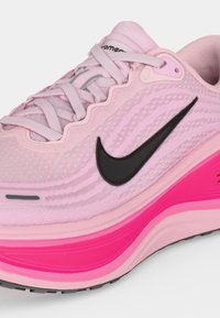 Κοντινό πλάνο ενός ροζ παπουτσιού Nike για τρέξιμο με μαύρο λογότυπο Swoosh, ανοιχτό ροζ κορδόνια και φωτεινή ροζ σόλα.