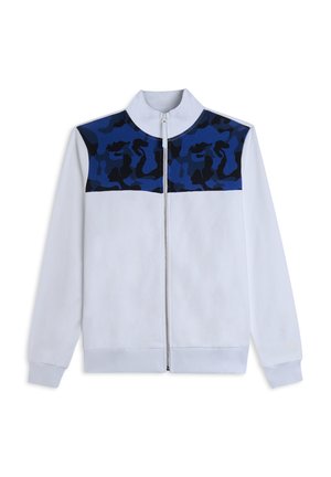 Chaqueta blanca con cremallera, con un patrón de camuflaje en azul y negro en los hombros y la parte superior del pecho, que cuenta con mangas largas y un cuello alto.