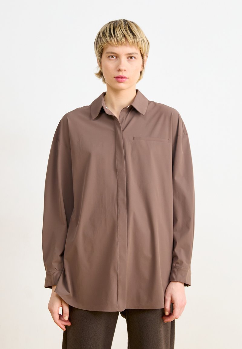 Camicia button-up marrone realizzata in tessuto leggero con una vestibilità rilassata, dotata di taschino sul petto, colletto e maniche lunghe con polsini.
