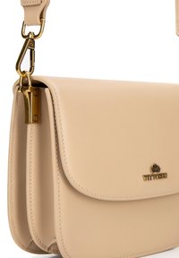 Borsa a mano in pelle beige con texture liscia, chiusura a pattina e dettagli in hardware dorato. Presenta un logo di marca sul davanti.
