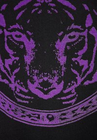 Il tessuto nero presenta una grafica prominente di una tigre viola, con dettagli intricati e accenti testurizzati attorno al design.