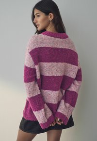 Strickpullover mit pinken und fuchsiafarbenen Streifen. Strukturierter Wollstoff, lockere Passform, überschnittene Schultern und weite Ärmel. Lässiges Design.