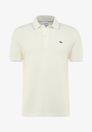 Polo en coton crème à manches courtes, avec un col bleu clair et un petit logo crocodile vert sur la poitrine gauche.