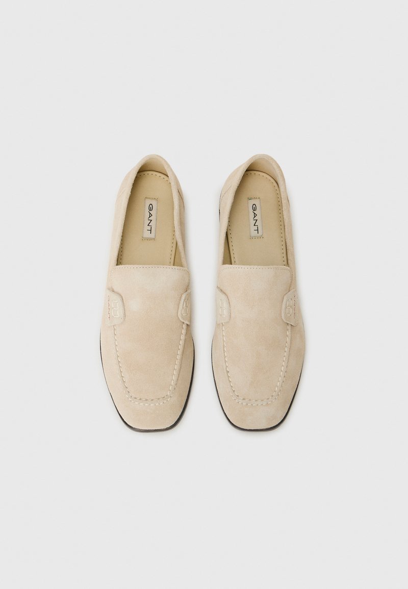 Mocassini in suede beige con dettagli cuciti lungo il bordo, texture liscia e logo GANT sulla soletta. Design classico slip-on.