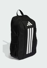 Czarny plecak z białym wzorem w trzy pasy, z tkaninowym wnętrzem, siateczkowymi kieszeniami bocznymi i uchwytem do przenoszenia na górze; kompaktowy i zorganizowany kształt.