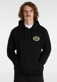 Felpa nera in misto cotone con tasca a marsupio. Presenta un grande toppe del logo Vans verde sul petto e cappuccio con cordini.