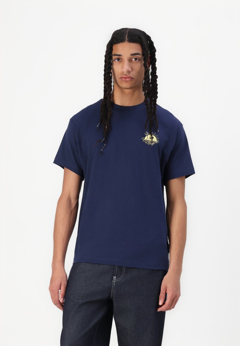 Camiseta de algodón azul marino de manga corta, con un gráfico de atardecer amarillo en el pecho. Diseño de corte recto, ajuste relajado.