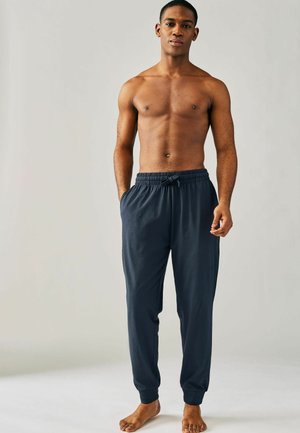 Marineblaue Jogginghose mit einem elastischen Bund und Zugband, ausgestattet mit Seitentaschen und schmal zulaufenden Bündchen. Glattes, leichtes Material.