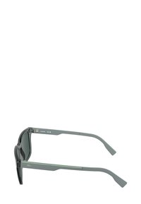 Occhiali da sole grigi con accenti verdi, caratterizzati da una montatura geometrica elegante, lenti scure e aste sottili con un dettaglio di logo discreto.