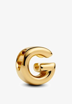 Scultura in metallo dorato a forma di lettera "G" con superficie liscia e riflettente e bordi arrotondati, che presenta un design moderno.