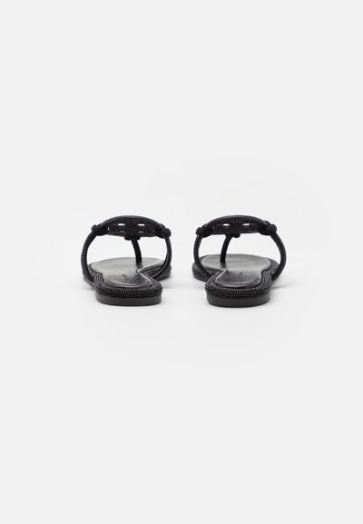 Sandales noires avec des brides tressées, semelles plates et semelle intérieure texturée. Design minimaliste avec un dos ouvert et une zone pour les orteils pour une meilleure respirabilité.