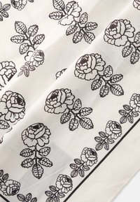 Tejido blanco con un patrón floral negro que presenta rosas y hojas, con un detalle intrincado y una disposición uniforme en todo el material.