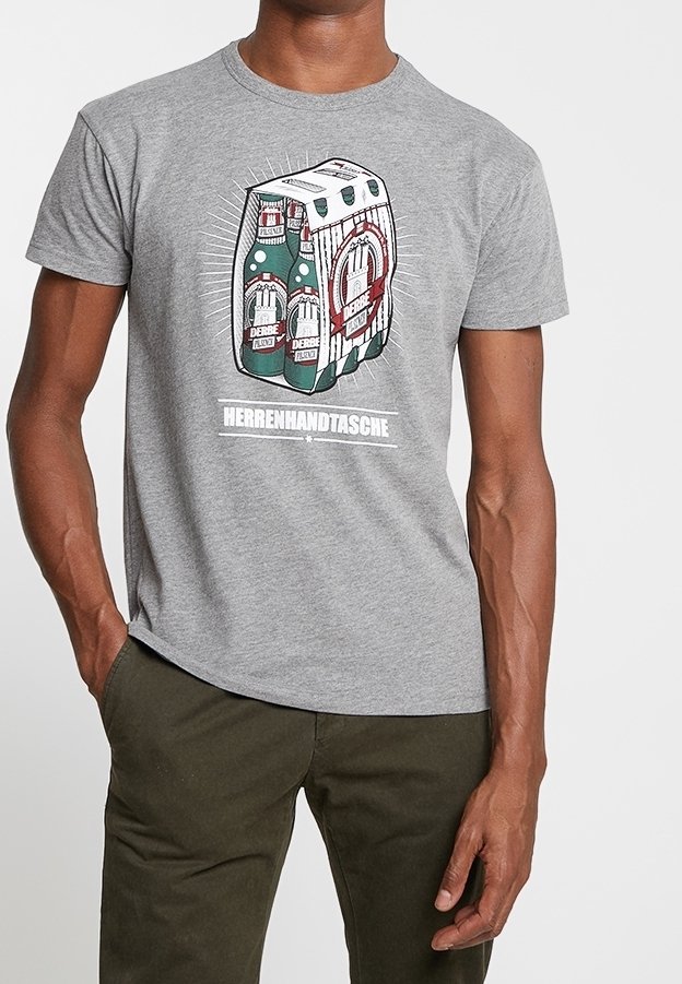 Homme portant un t-shirt gris avec un graphique représentant un pack de six bouteilles de bière verte étiquetées "Derbe Flavour" et le mot "Herrenhandtasche".