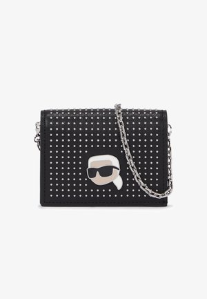 Czarny skórzany portfel zdobiony srebrnymi ćwiekami, z łańcuszkowym paskiem i akcentem w postaci kreskówkowej twarzy. Kompaktowy prostokątny kształt.